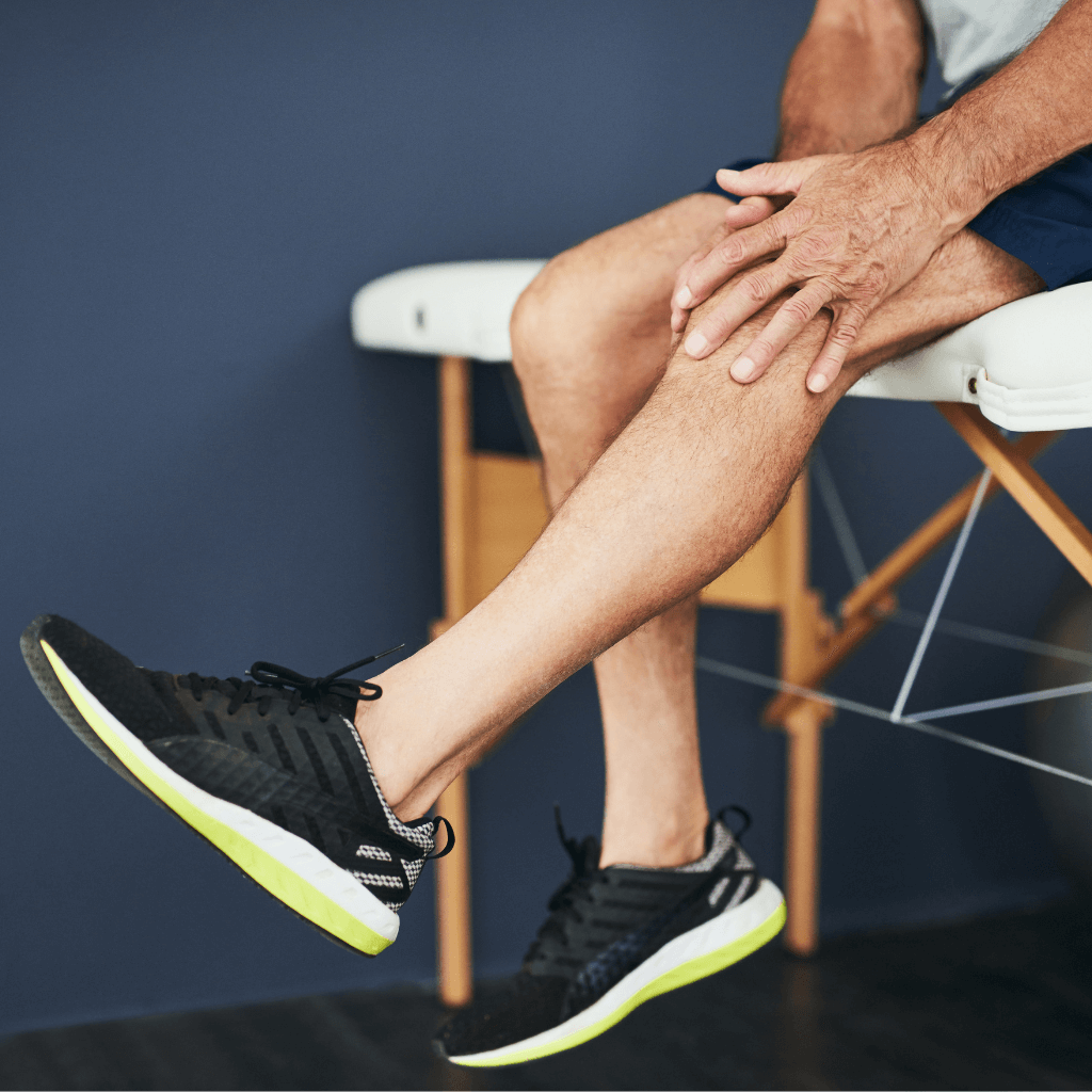 close up of a mans legs as he holds his knee at a physio